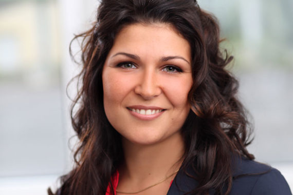 Brünette Frau vor unscharben Hintergrund beim Bewerbungsfotoshooting.