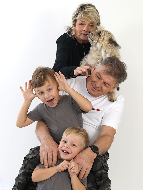 Großeltern, Enkeln und Familienhund lachend im Fotostudio.