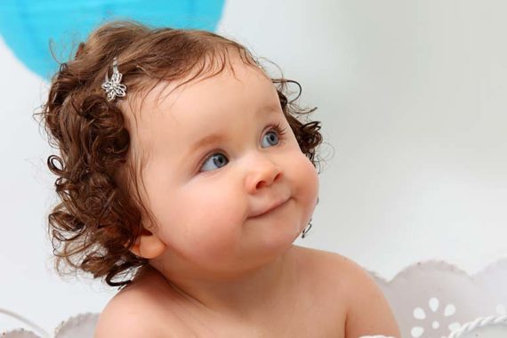 Kleines Mädchen in der Blechbadewanne mit Deko im Hintergrund.