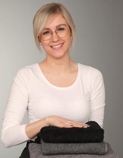 Haushaltshilfe Blonde Frau mit beigen Shirt und Handtüchern